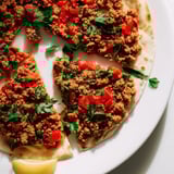 Golden-crusted Turkish Lahmacun flatbread topped with flavorful minced meat and vibrant vegetables, ready to eat.