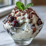 Fluffy yogurt berry sundaes with dark chocolate shavings topped with fresh mint and juicy berries in elegant glasses.