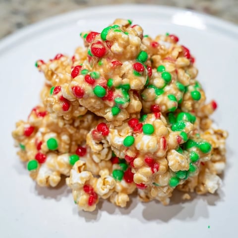 Warm, sticky popcorn piles glistening with holiday sprinkles, perfect for sharing and holiday treats.