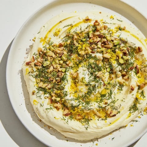 Creamy butter board charcuterie laden with toasted nuts and herbs, ready to be enjoyed with crusty bread.