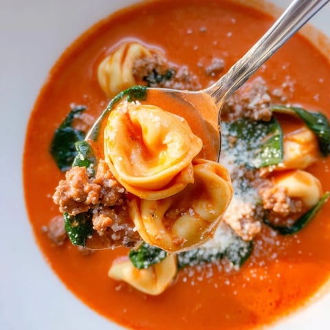 A cozy bowl of Tuscan Tortellini Soup with creamy tomato broth, cheese-filled pasta, and wilted spinach.