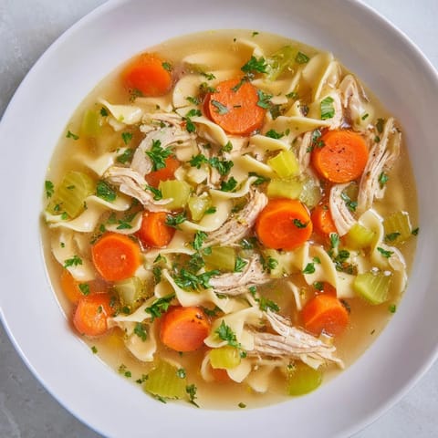 Homemade Classic Chicken Noodle Soup, a comforting meal with golden egg noodles and fresh herbs.