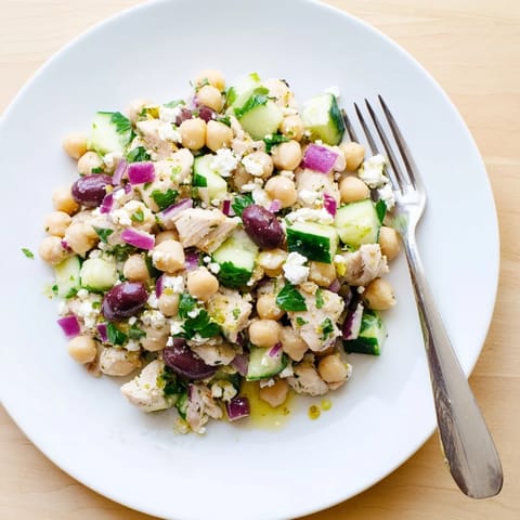 A vibrant Mediterranean Chickpea Chicken Salad in a white bowl, featuring cherry tomatoes, Kalamata olives, and fresh parsley.