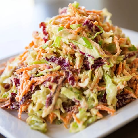Bright green and purple cabbage mix tossed with shredded carrots in a creamy, tangy dressing, showcasing the Best Cabbage Coleslaw in a rustic bowl.  