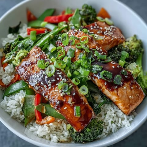 A vibrant teriyaki salmon bowl with glistening fish, fluffy white rice, and colorful stir-fried broccoli and peppers ready to serve.