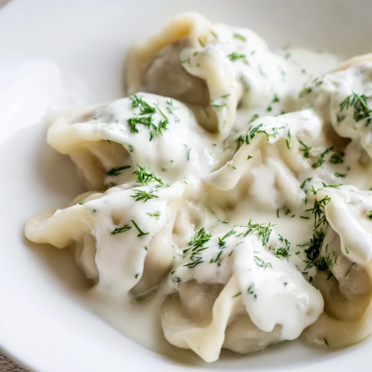 Golden, perfectly formed Russian Pelmeni sit in a bowl, a comforting and flavorful meat dish.