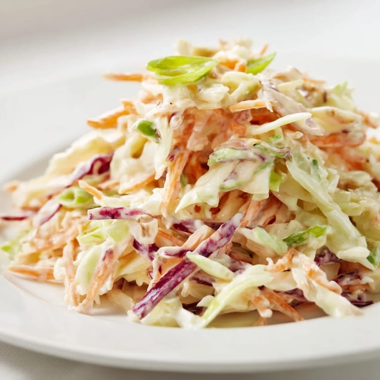 Freshly made Best Cabbage Coleslaw with vibrant green and purple cabbage, carrots, and green onions, ready to serve chilled at a picnic.
