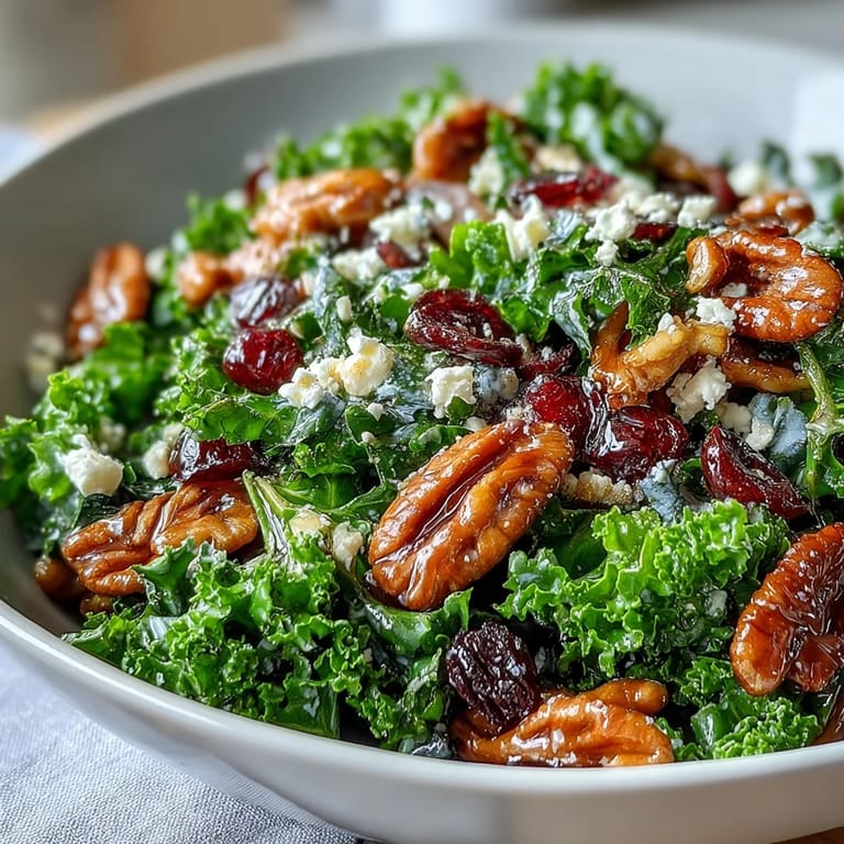 Vibrant green kale salad tossed with sweet maple mustard glaze, sliced red onion, crumbled feta, and crunchy pecans for a hearty side dish.  