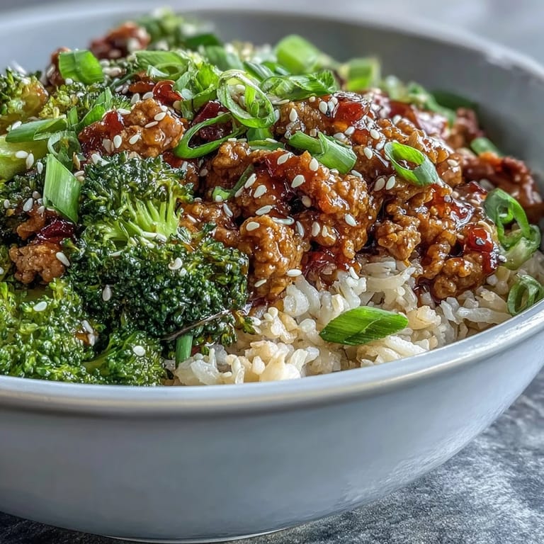 Steam rises from bowls of nutty brown rice topped with glazed ground turkey, crisp broccoli florets, and a sprinkle of green onion and sesame seeds.