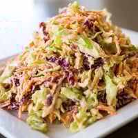 Bright green and purple cabbage mix tossed with shredded carrots in a creamy, tangy dressing, showcasing the Best Cabbage Coleslaw in a rustic bowl.  