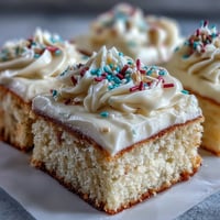 Fluffy vanilla sheet cake topped with creamy buttercream and graduation-themed sprinkles, ready for celebration.