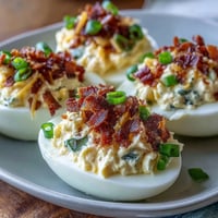 Spicy jalapeño popper deviled eggs topped with crispy bacon and fresh jalapeño slices. Creamy, tangy, and perfect for parties.
